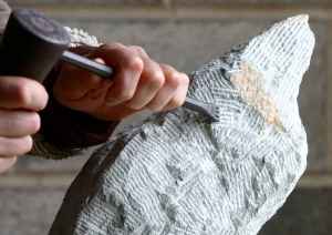 sculptor chiseling art from rock